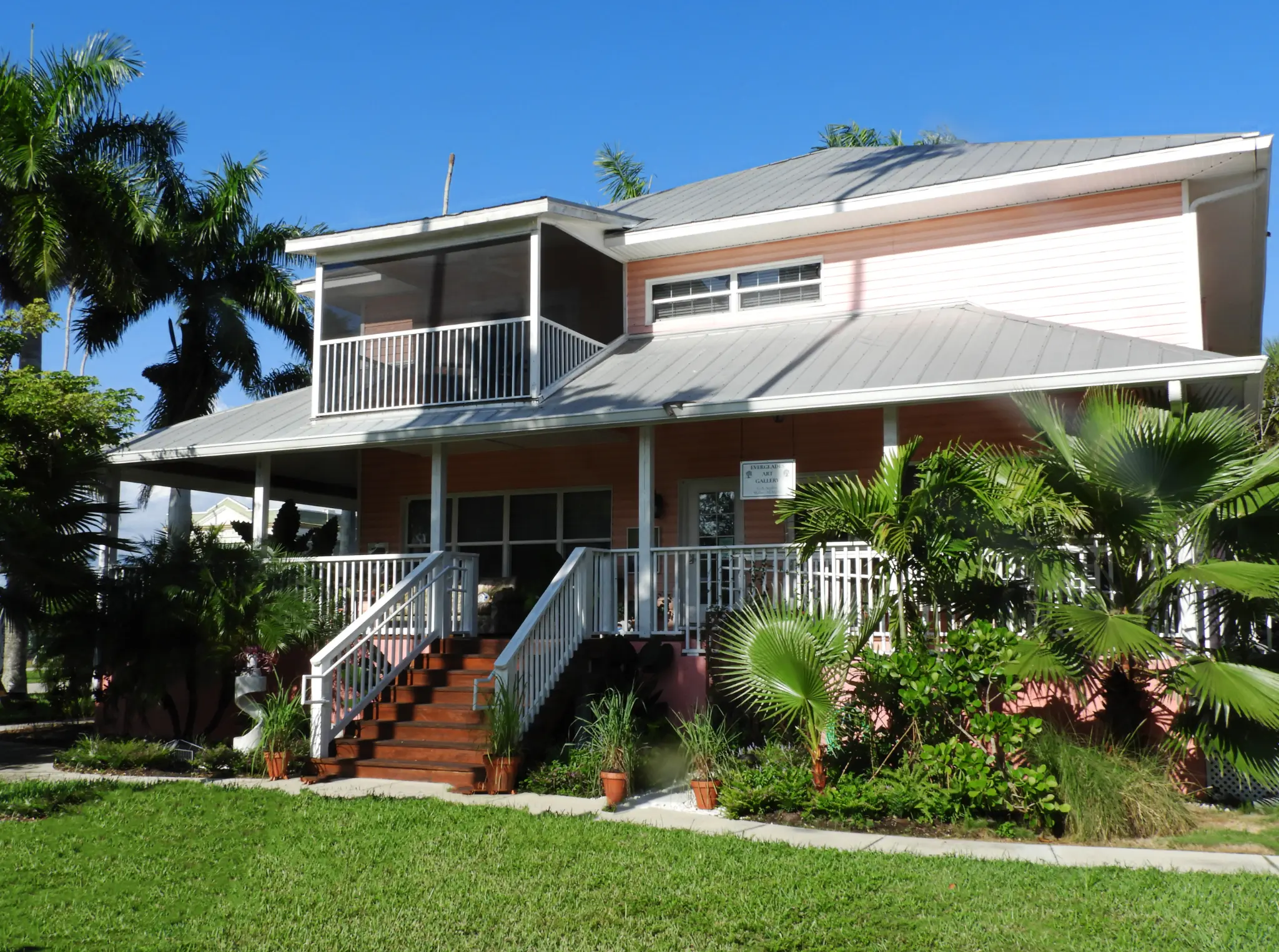 The peach exterior and tropical garden of 4th Quarter Everglades Art Gallery